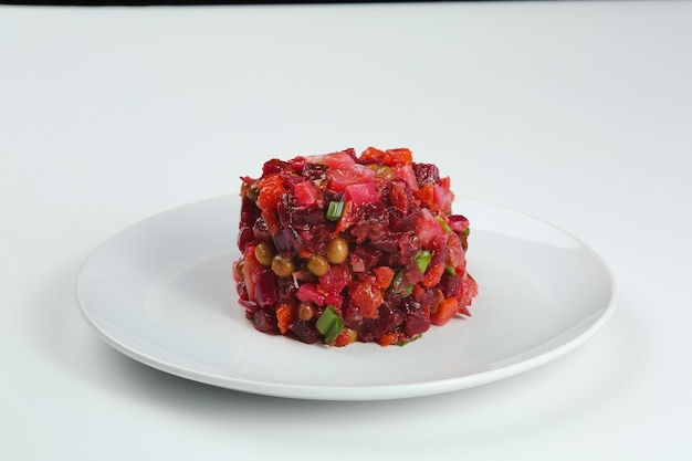 Vinaigrette salad in white plate isolated on white background. Traditional russian beetroot salad with boiled vegetables