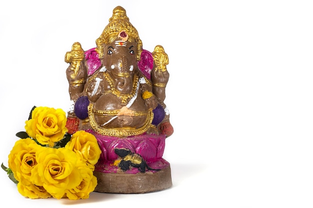 Foto statua di vinayaka chaturthi ganesh fatta di argilla con fiori gialli su sfondo bianco