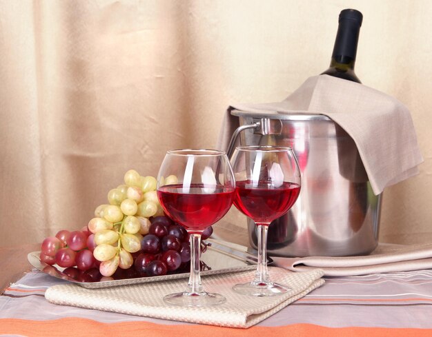 Вино и бокалы на круглом столе на фоне ткани