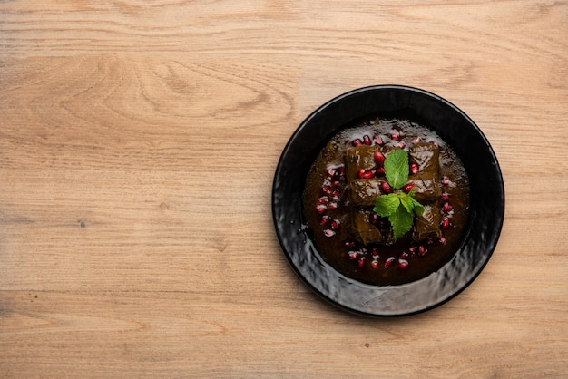 Vine leaves with pomegranate seeds and sauce served in dish isolated on table top view of arabian food