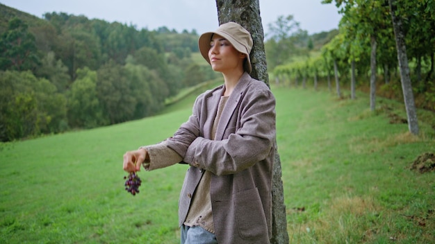 Vineyard farmer enjoying plantation at autumn woman holding grape cluster