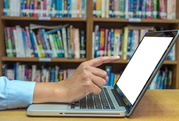 Vinger die op het scherm van laptop computer over de houten lijst in bibliotheek, Onderwijs Technolog richten