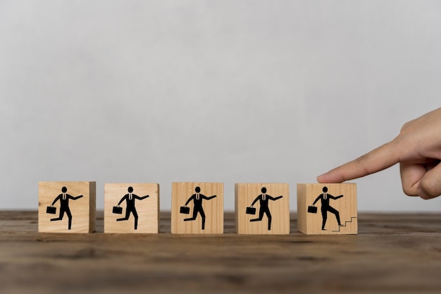 Vingers die een houten blok aanraken, tonen een zakenman die zijn loopbaanontwikkeling op een houten blok loopt