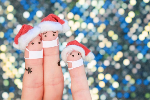 Vingerskunst van familie met medisch masker van COVID-2019 viert Kerstmis. Concept mensen in nieuwjaarshoeden.