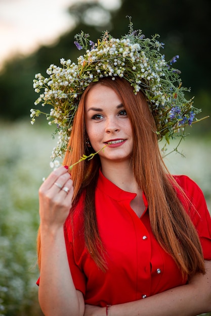 Vinnytsia Ukraine June 18 2021 Redhead girl at sunset in a chamomile field with a wreath