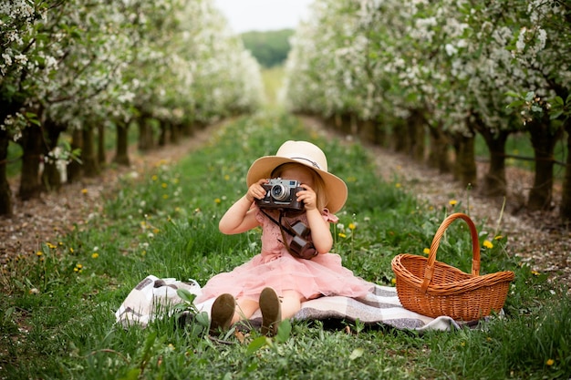 Photo vinnytsia ukraine may 18 2021 little girl with a camera in a flower garden copy space