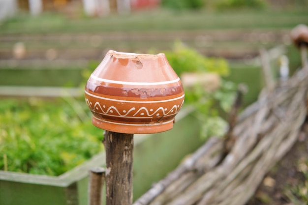 Vintage aarden pot op het rieten hek Traditionele keramische pot op het hek een dorpstraditie