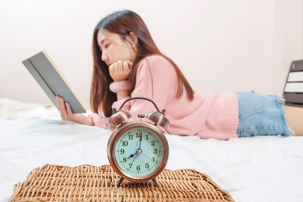 Vintage Alam klok show tijd voor tiener meisje het lezen van een boek op bed kamer.