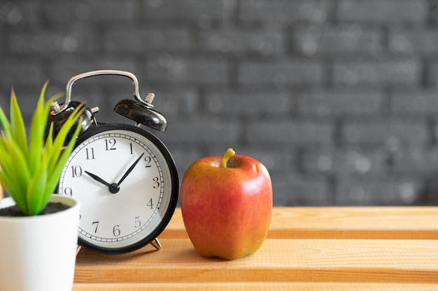 Vintage alarm clock and apple on wooden desk