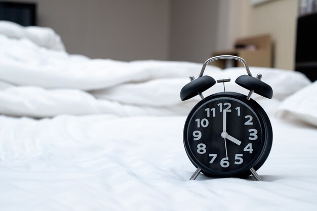 Vintage alarm clock on the bed in bedroom at home, wake up or bed time concept.