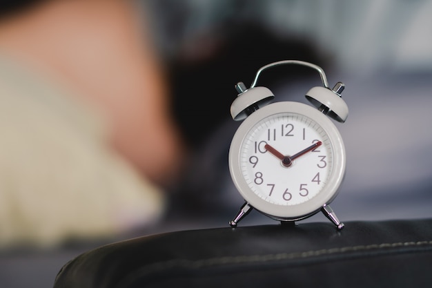 A vintage alarm clock is placed on the head of the bed. Conceptual media 