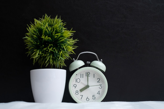 Vintage alarm clock and little decoration tree on the bed