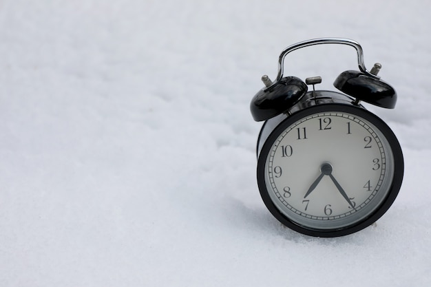 Photo vintage alarm clock on snow white.