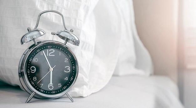 Vintage alarm clock on white bed Time concept