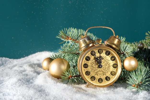 Vintage alarm clock with fir twigs gold trinkets and berries Time ten to midnight Dark green background with snow Merry Christmas and Happy New Year