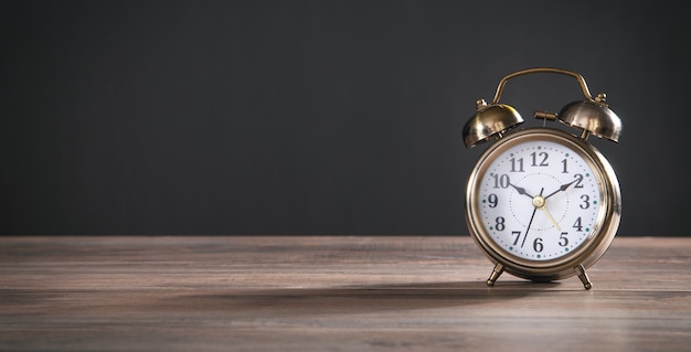 Vintage alarm clock on the wooden table.