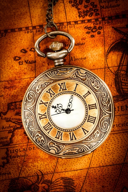 Orologio da tasca antico vintage su un'antica mappa del mondo nel 1565..