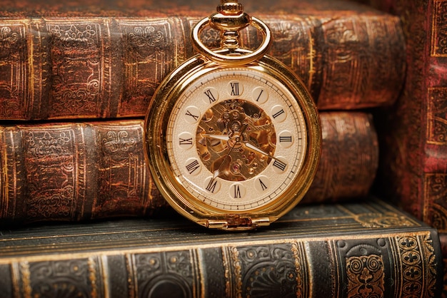 Старинные антикварные карманные часы на фоне старых книг