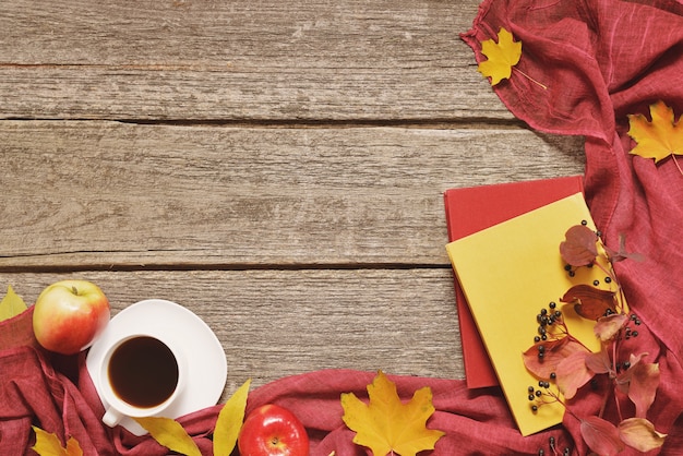 Tavola d'annata di autunno con le mele, le foglie cadute, la tazza di caffè o il tè sul vecchio fondo di legno della tavola