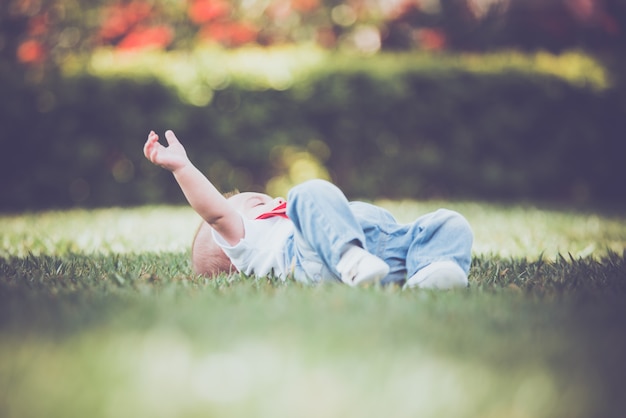 Vintage baby boy with red suspender in outdoor - lying on the grass