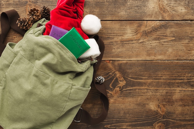 Vintage backpack with santa claus hat and passports on wooden table. 