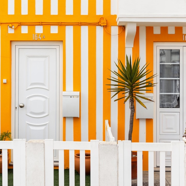 Винтажный красивый полосатый желтый дом с дверьми, белым почтовым ящиком и пальмой на террасе