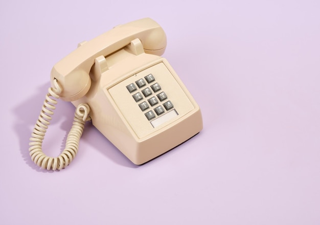 A vintage beige phone stands on the table Old style telephone