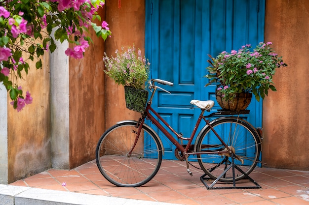 Vintage bike with basket full of flowers next to an old building in Danang