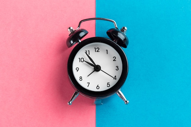 Vintage black alarm clock on a color block 