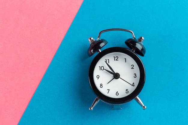 Vintage black alarm clock on a color block 