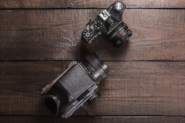 Vintage black film camera on the brown background of natural wood with the lens