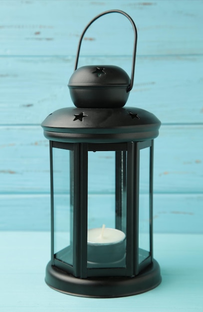 vintage black lantern with candle on blue wooden background top view