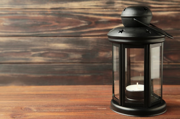 Vintage black lantern with candle on brown wooden background Top view