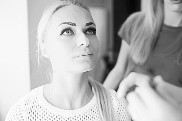 vintage black and white photo of a girl with professional make-up / strict make-up on the face of a beautiful professional model in a beauty salon