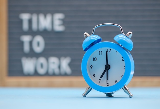 Vintage blue alarm clock at the background of the inscription is the time to work on the English language