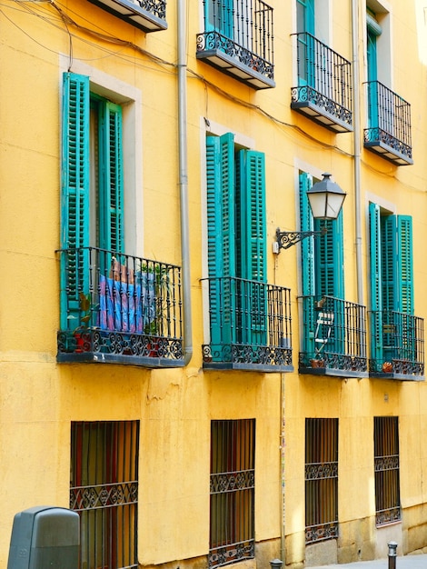 스페인 마드리드 시내의 선명한 노란색 외관에 있는 빈티지 블루 발코니