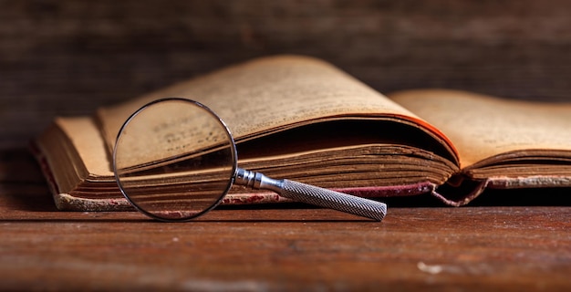 Vintage book and magnifying glass on wooden desk