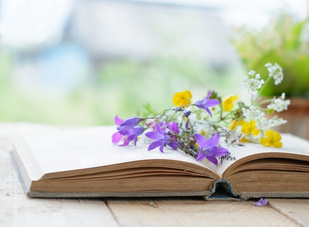 Vintage book with bouquet of wild flowers, nostalgic vintage surface