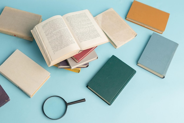 Vintage books and magnifying glass on light blue background Education background World books day