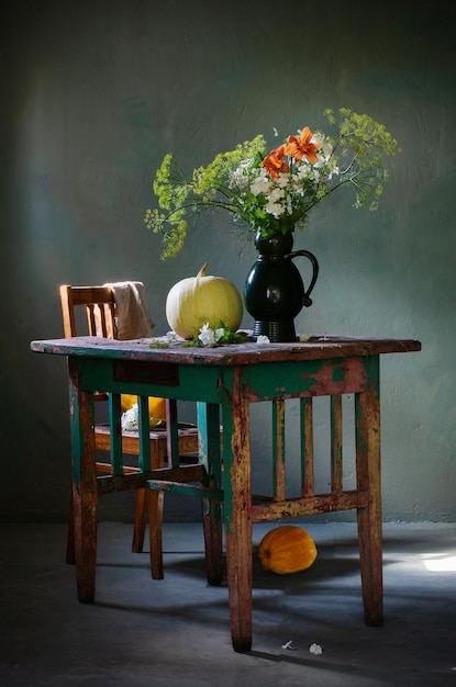 Bouquet vintage con aneto in brocca di ceramica e zucche sul vecchio tavolo di legno