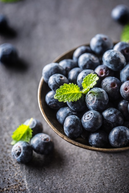 Vintage bowl full of fresh blueberries with herbs.