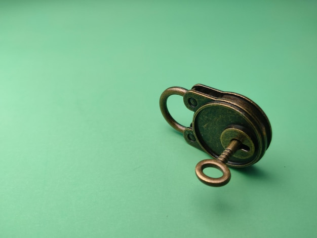 Vintage bronze key and padlock on soft green paper background image with copy and text space