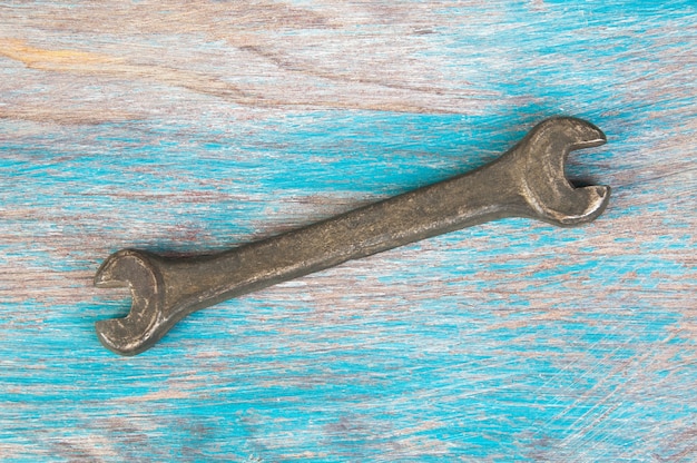 Vintage bronze wrench on shabby blue wooden background. Copy space for text.