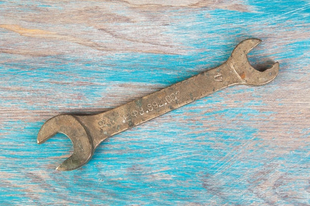 Vintage bronze wrench on shabby blue wooden background. Copy space for text.