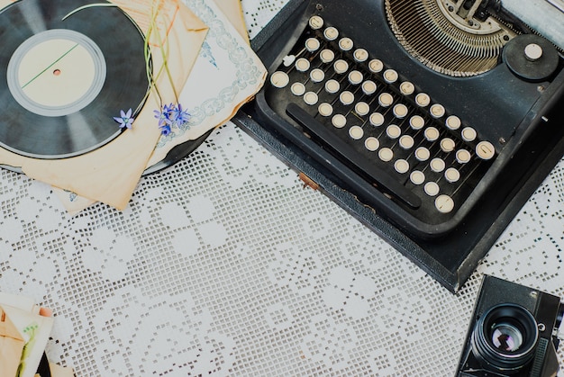 Foto vintage bureau met typemachine, stapel vinyl en camera op tafellaken