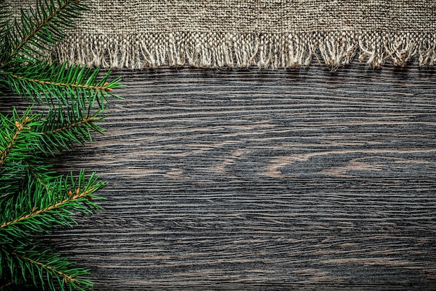 Vintage burlap fur branch on wooden board Christmas background