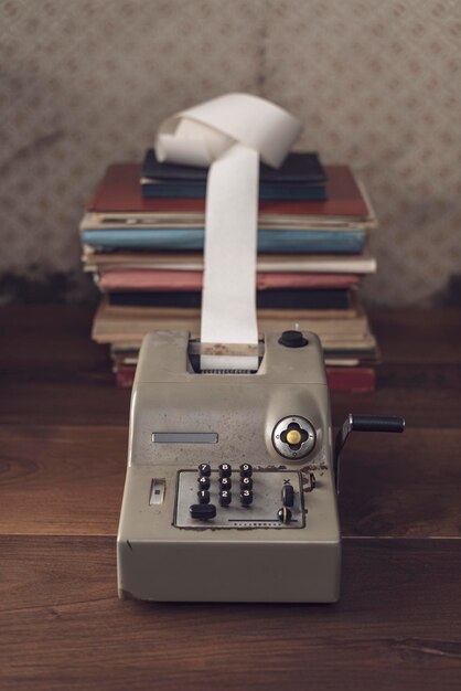 Vintage calculator with handle and paper roll on the accountant desk finance and business concept