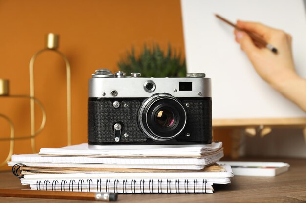 Vintage camera and notepads on wooden table on orange background