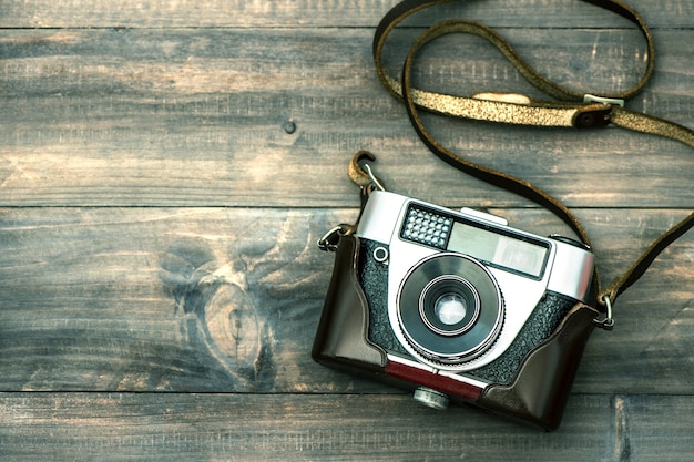 Foto vintage camera op houten achtergrond. bovenaanzicht. getinte foto in retrostijl