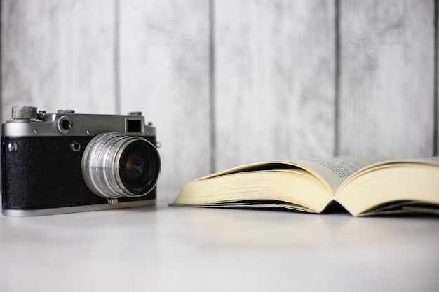 Vintage camera next to an open book on a light background